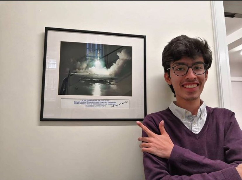 Image of a man smiling and pointing at photo of the Apollo moon landing