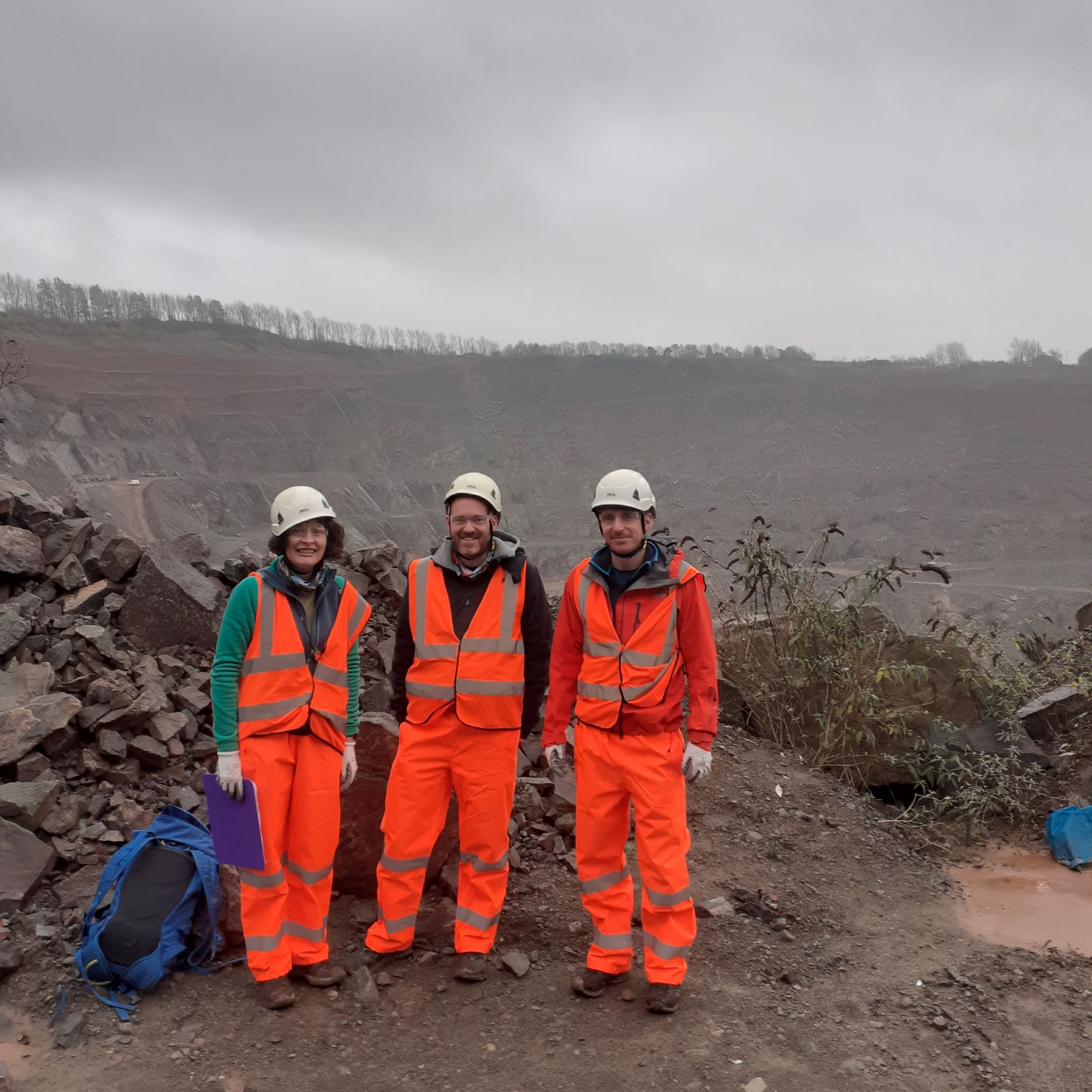 Photo of three people stood at the edge of a quarry wearing protective gear