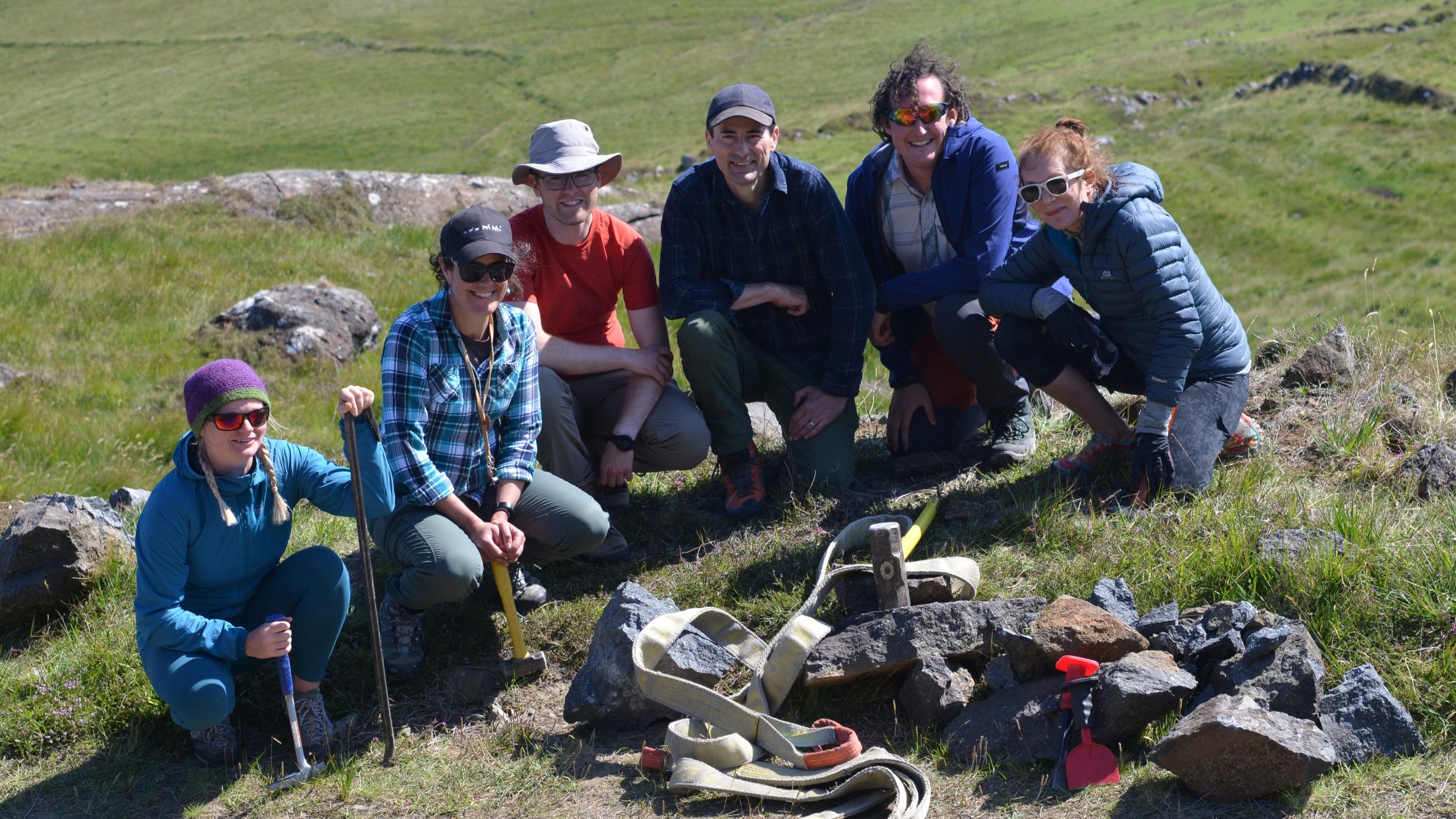 Photo of six people knelt on the ground, with rock samples in front of them