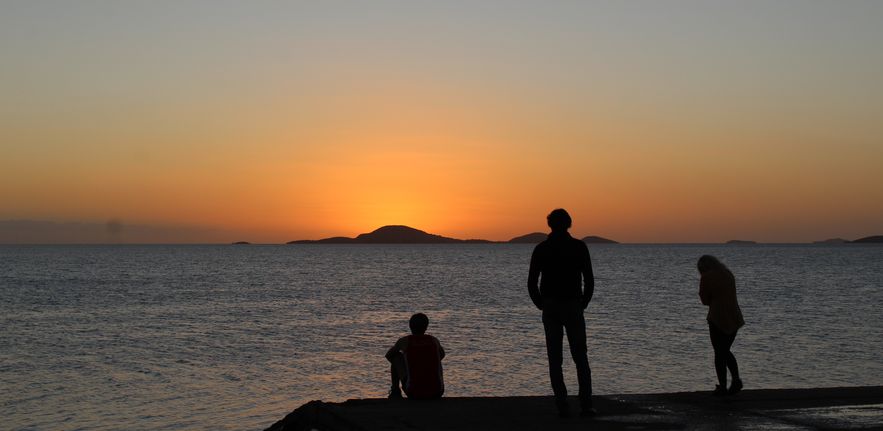 Photo of the sun setting over the sea in New Caledonia, with the mapping group in silhouette