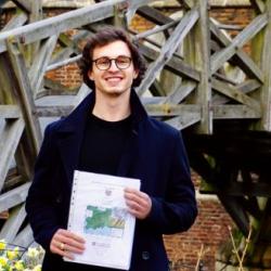 Photo of a man smiling holding his dissertation