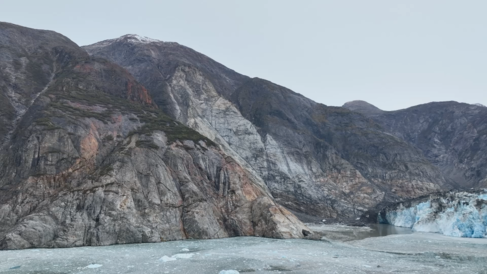 Photo of mountainous landscape with a glacier front on the right and water in the foreground