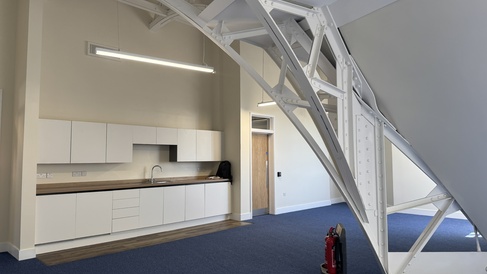 Photo showing kitchen area with metal trusses arcing in the foreground