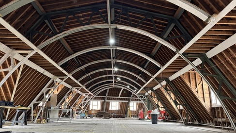 Photo showing loft of Sedgwick Building exposed during recent works. Arcing across the ceiling are the original metal trusses.