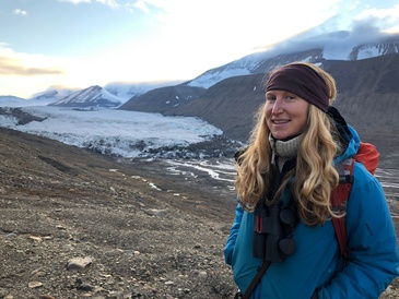 Image of Gabby stood smiling in front of a glacier