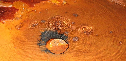 Image of rust brown water with bubbles rising 