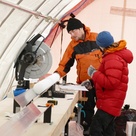 Two people working in an ice core drilling tent, examining an ice core
