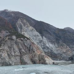 Photo of mountainous landscape with a glacier front on the right and water in the foreground