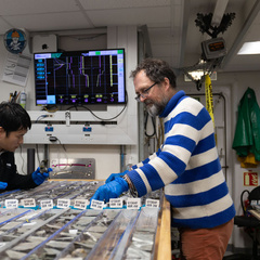 Photo of two men examining cores of rock laid out on a table.