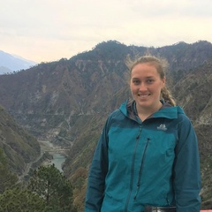 Photo of Aisling on field work, standing in front of mountains, in December 2019