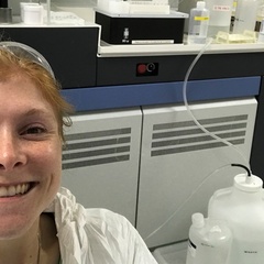 Women smiling in the lab with a mass spectrometer in the background