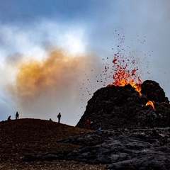 Photo showing a volcanic spatter cone erupting with lava coming out of the top
