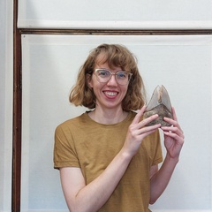 Photo of woman smiling holding giant shark tooth