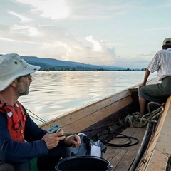 Image of two men on a boat sailing on a river