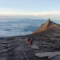 Photo of a sharp mountain peak with two people standing on the flanks