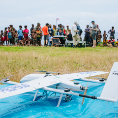 Drone ready to launch in the foreground with research scientists and Manam islanders gathered in the background; image credit Mathew Wordell