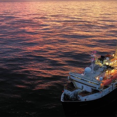 Image of sun setting behind drilling equipment on a ship