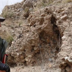 Grace standing next to a rock outcrop with a camera