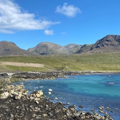 Photo taken on a beach looking up to the mountains, it is sunny