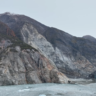 Photo of mountainous landscape with a glacier front on the right and water in the foreground
