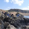 Photo of students sat on an outcrop with the Doon sill in the background