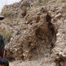 Grace standing next to a rock outcrop with a camera