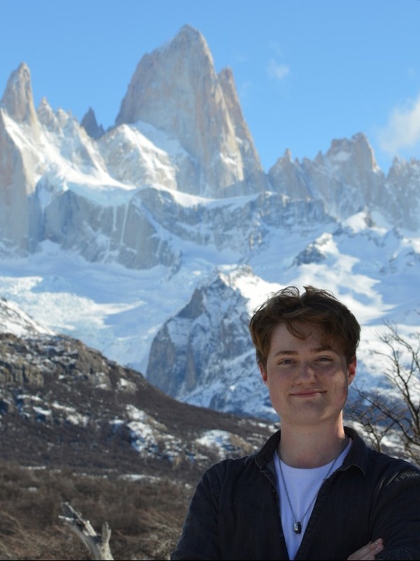Photo of Max stood in front of ice-clad mountains