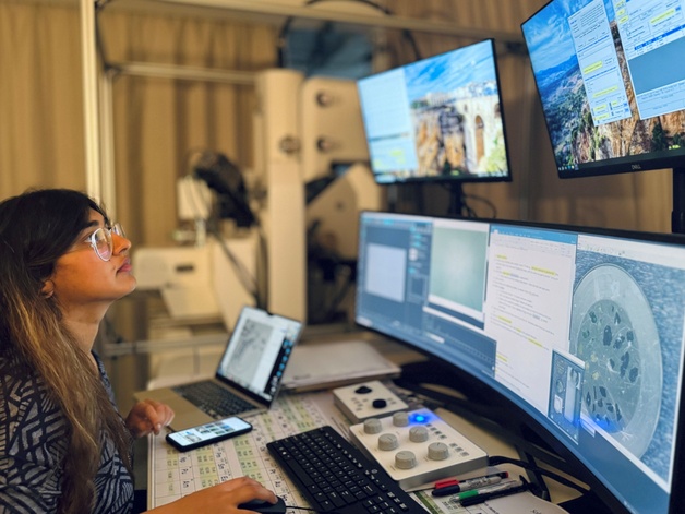 Photo shows person sat at a desk looking at computer screens