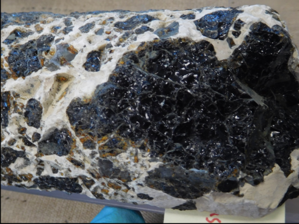 Photo of a core of rock containing dark glassy fragments encased in white groundmass