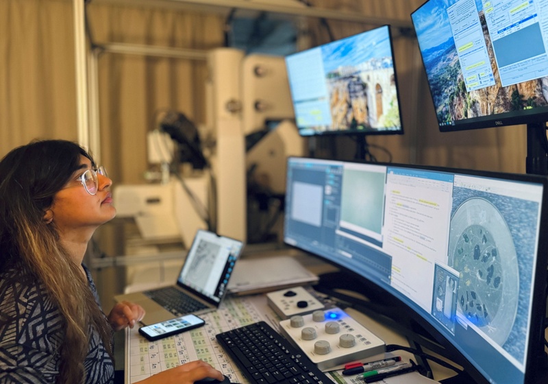 Photo shows person sat at a desk looking at computer screens