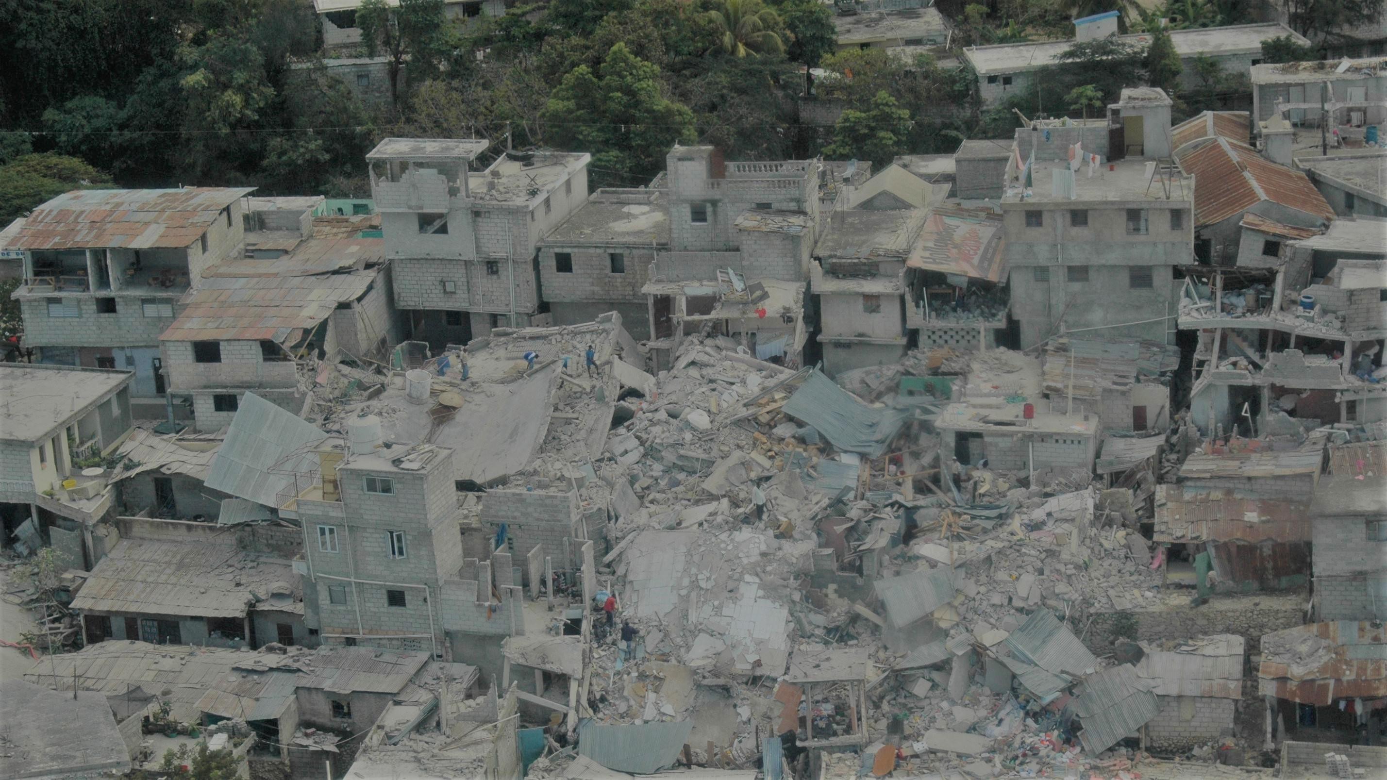 People standing amid the rubble of destroyed building. Credit: Vicente Raimundo EU/ECHO on Flickr Image showing people standing amid the rubble of destroyed building
