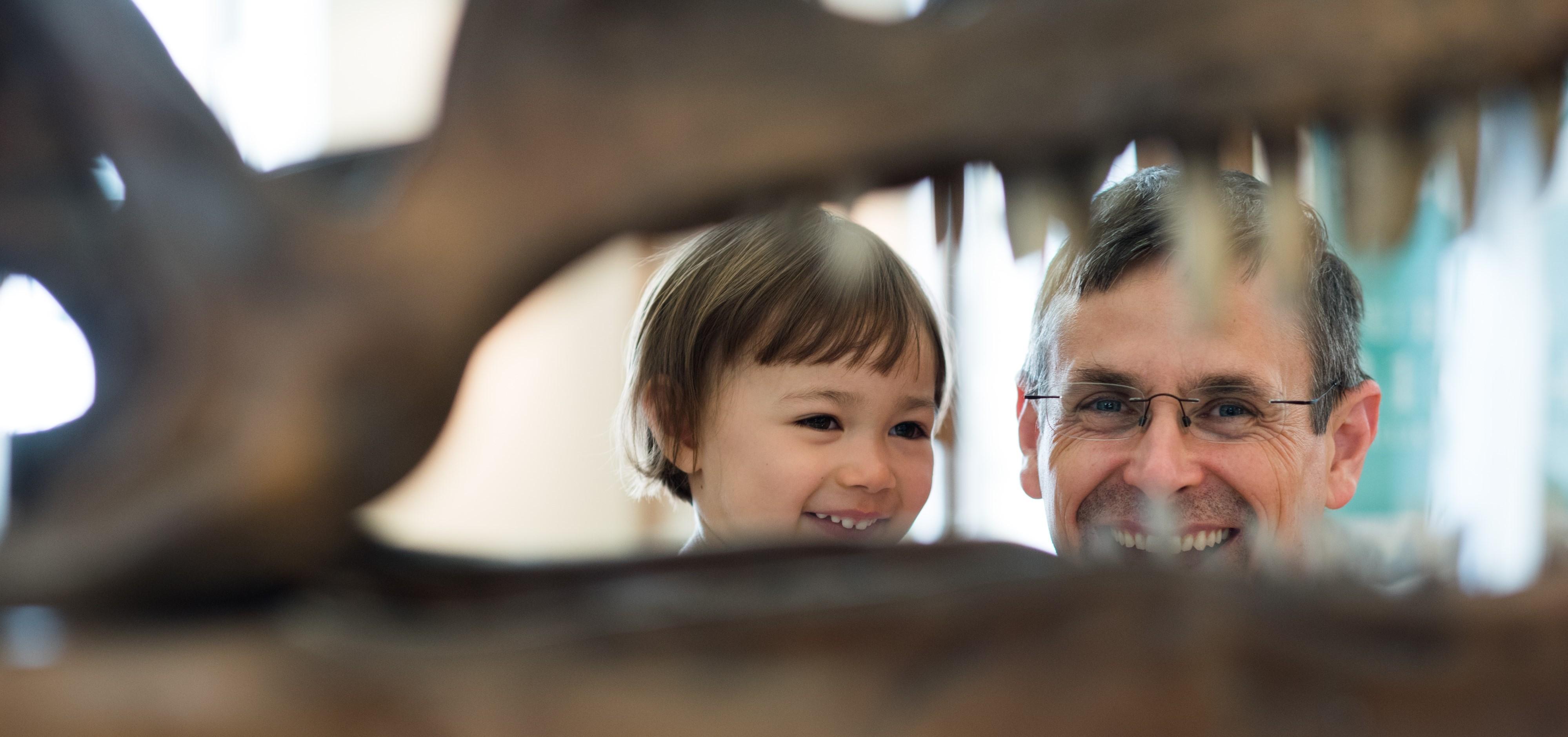 Image of a child and adult looking through the jaws of a dinosaur skull