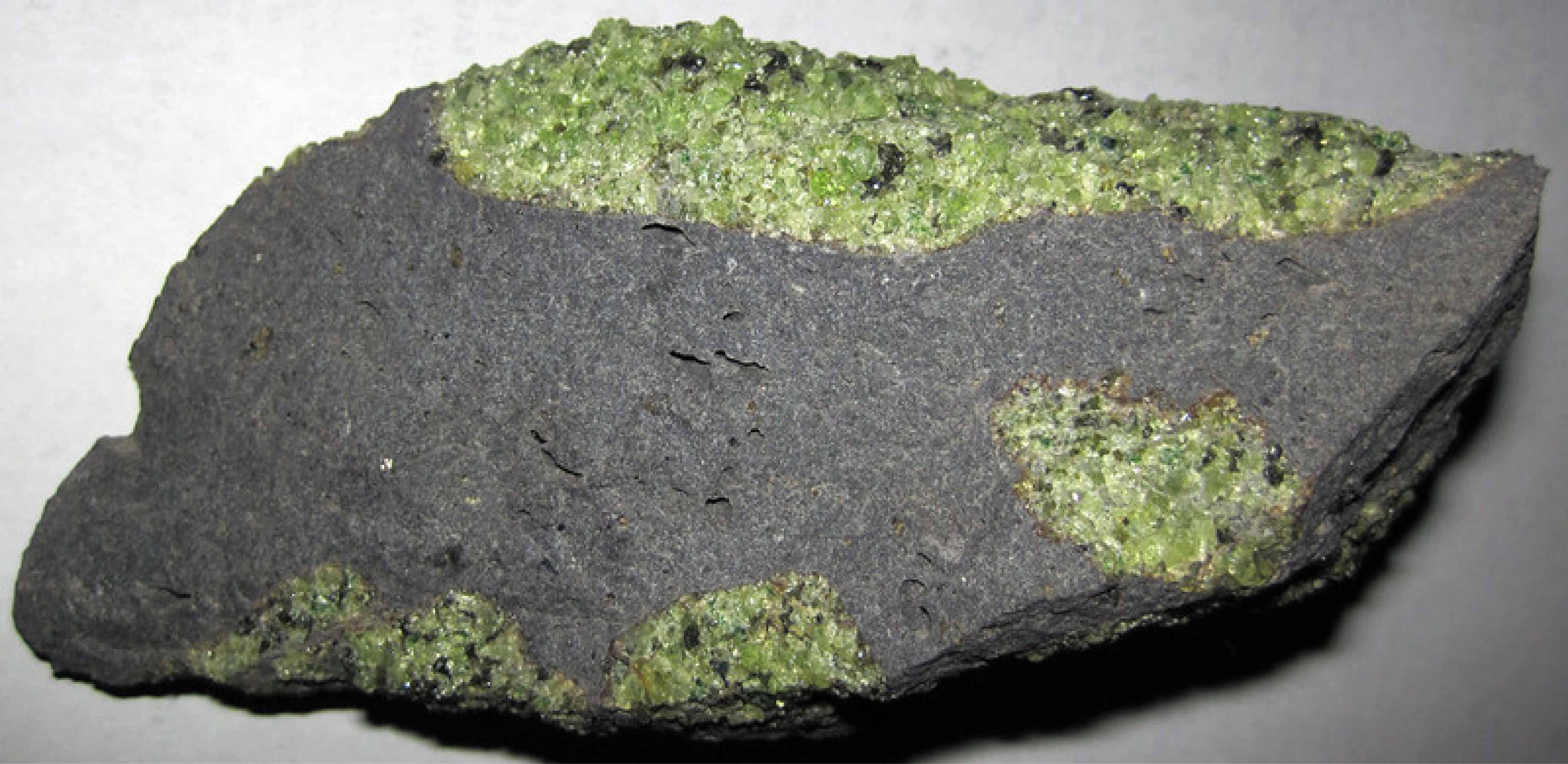 Chunks of exotic green rocks from the mantle erupted from the San Carlos Volcanic Field, Arizona. Credit: James St John on Flickr. Grey volcanic rock containing exotic green nodule: you can see the pistachio green olivine crystals they are made of