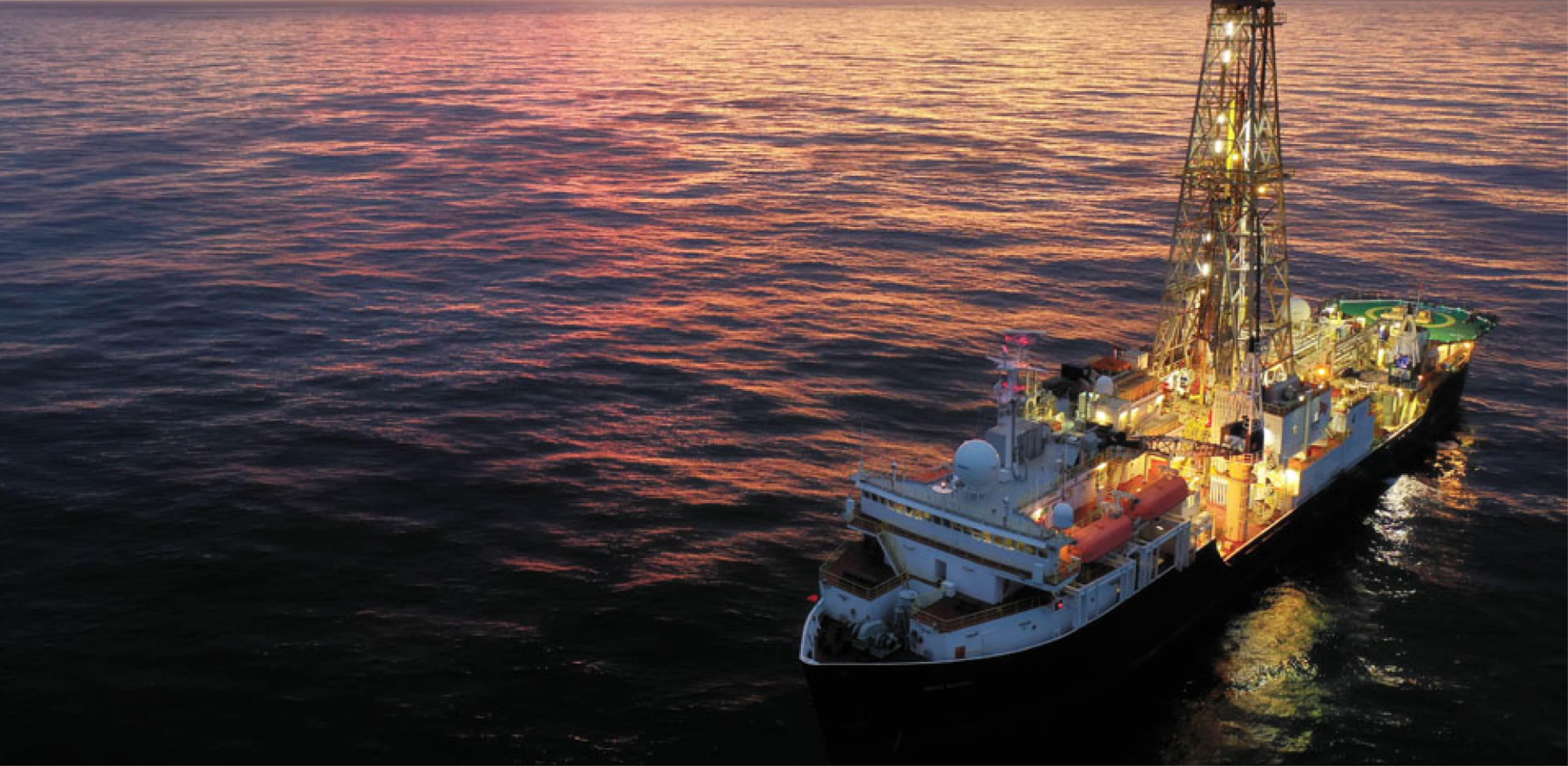 Image of sun setting behind drilling equipment on a ship