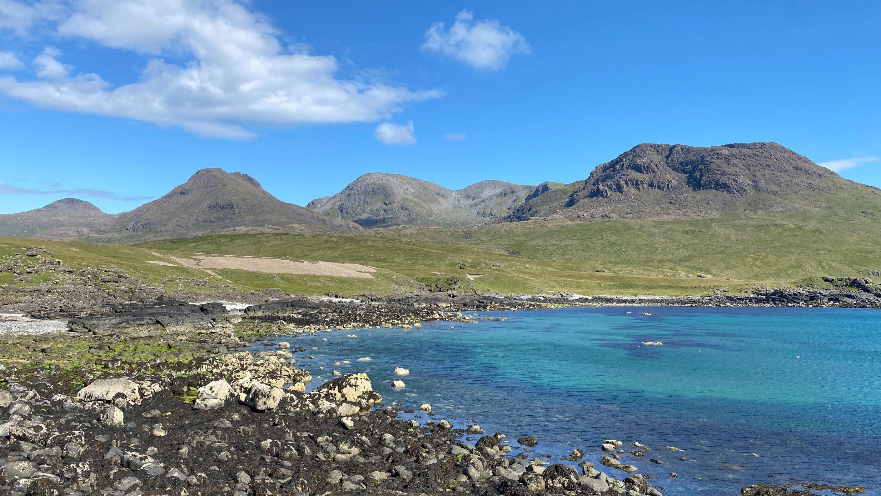 Photo taken on a beach looking up to the mountains, it is sunny