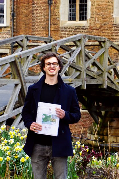 Photo of a man smiling holding his dissertation
