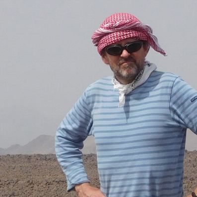 Image of Nicky standing with arms on hips at his field site in the desert