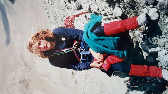Photo of John Smallwood sat down on rocks on field work, carrying climbing gear 