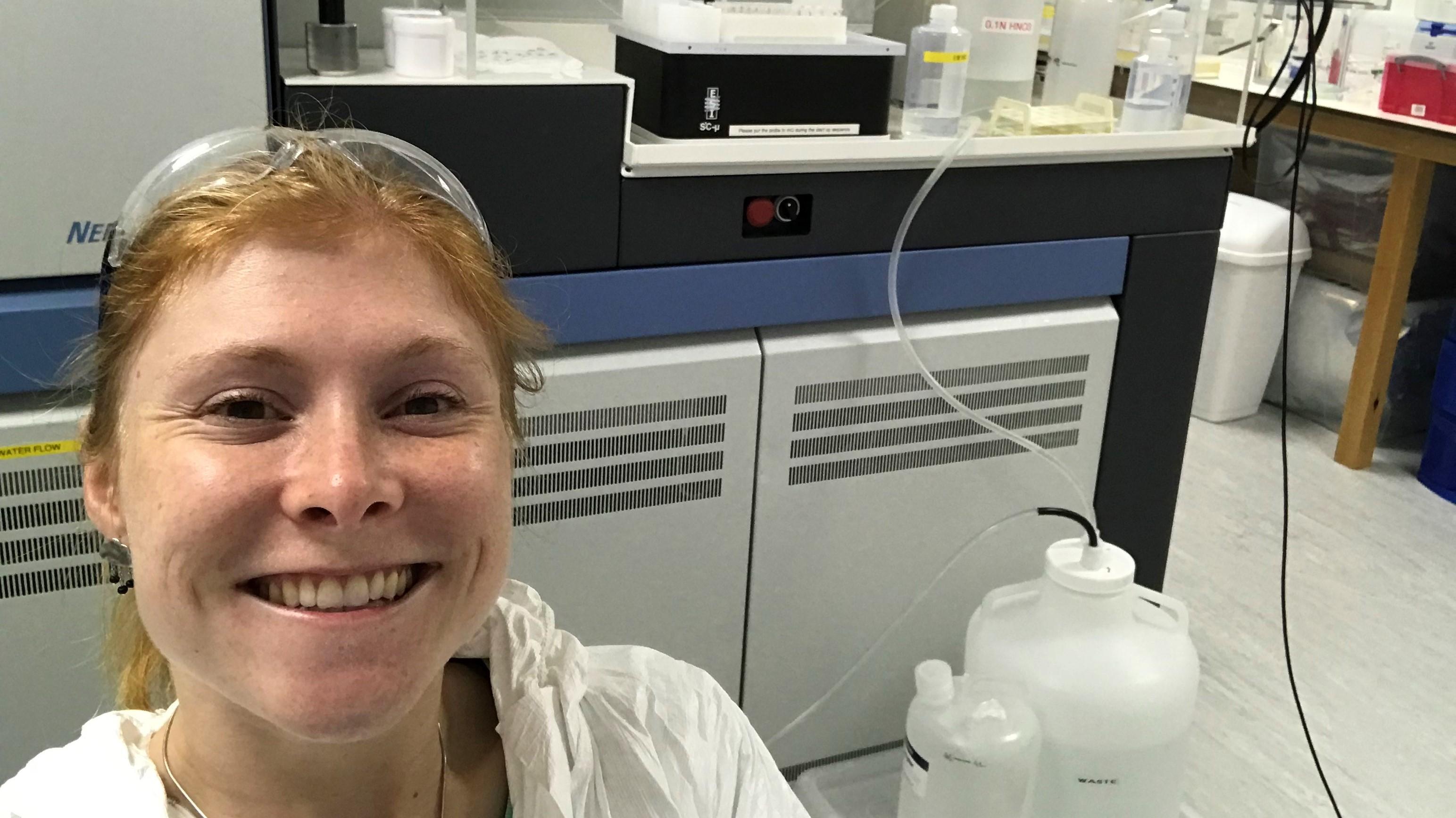 Women smiling in the lab with a mass spectrometer in the background