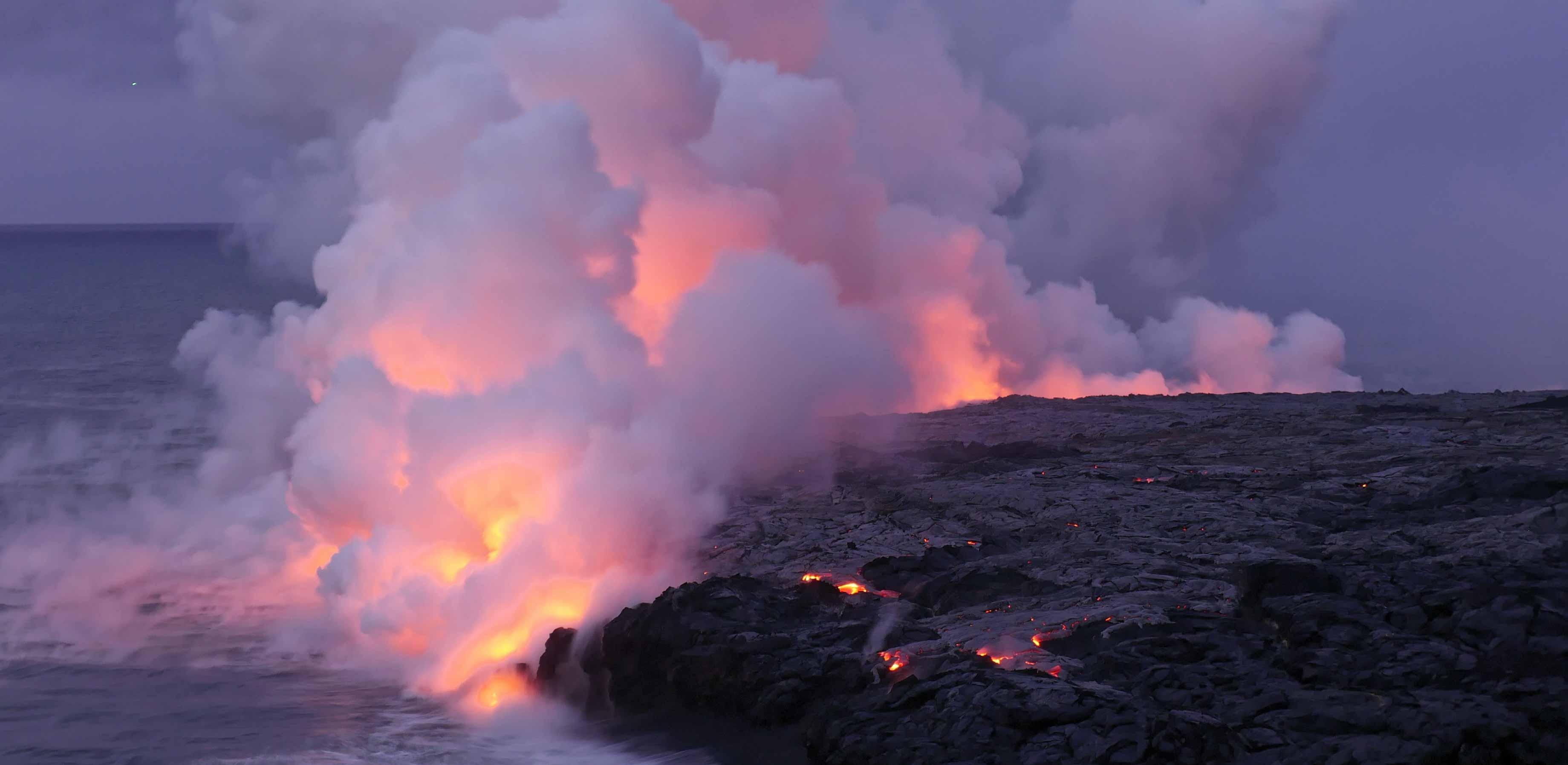 Image of lava flows in Iceland meeting the sea, with incandescent steam lofting